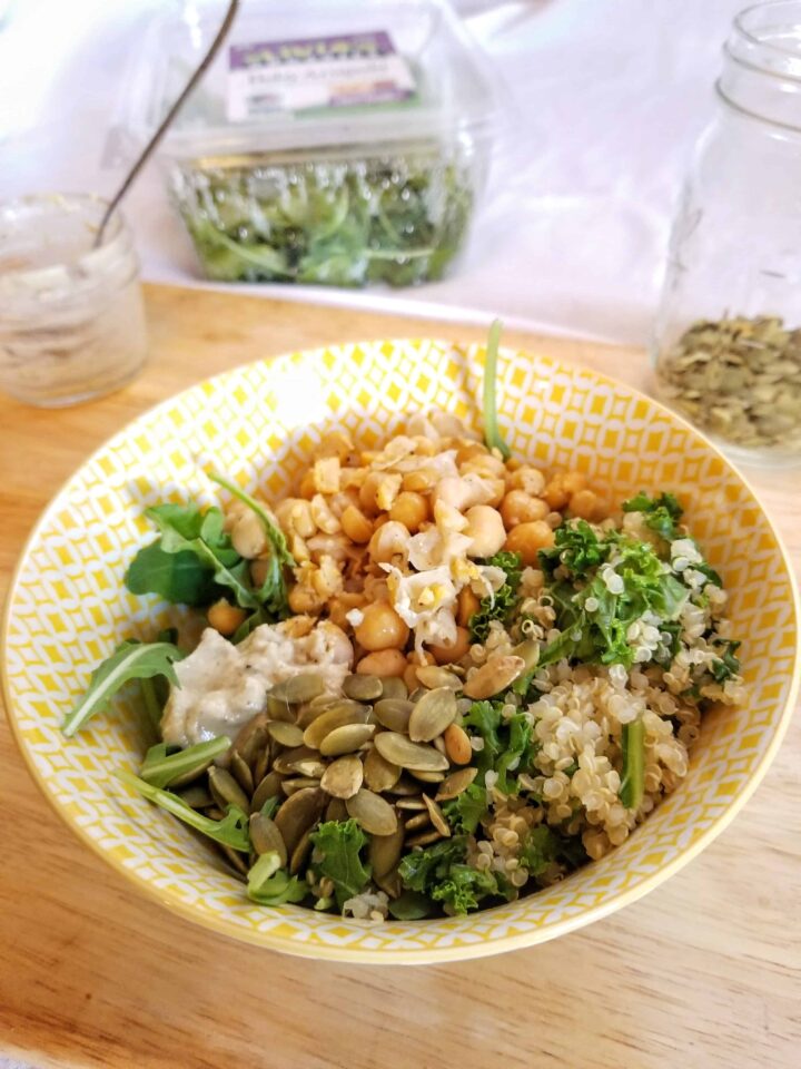 vegan caesar grain bowl with chickpeas and arugula in a yellow bowl