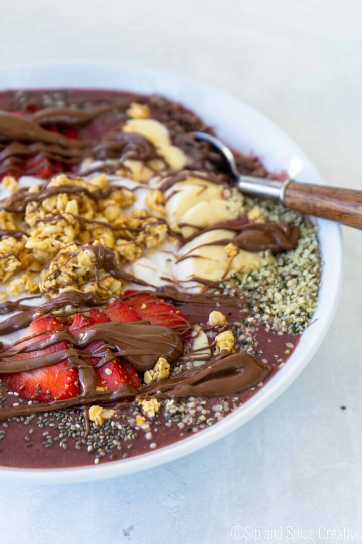 acai bowl topped with strawberries, chia seeds, hemp seeds, granola and bananas